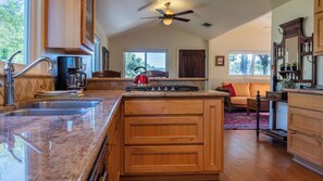 A spacious kitchen with granite countertops, wooden cabinets, and a central island. - Quercus Acorn Cottage by Avantstay 2 King Suites + Porch Walkable Downtown Paso Robles (Paso Robles)