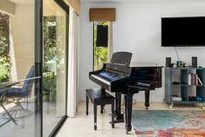 Ein modernes Wohnzimmer mit einem Flügel, einem Fernseher und einem Bücherregal.