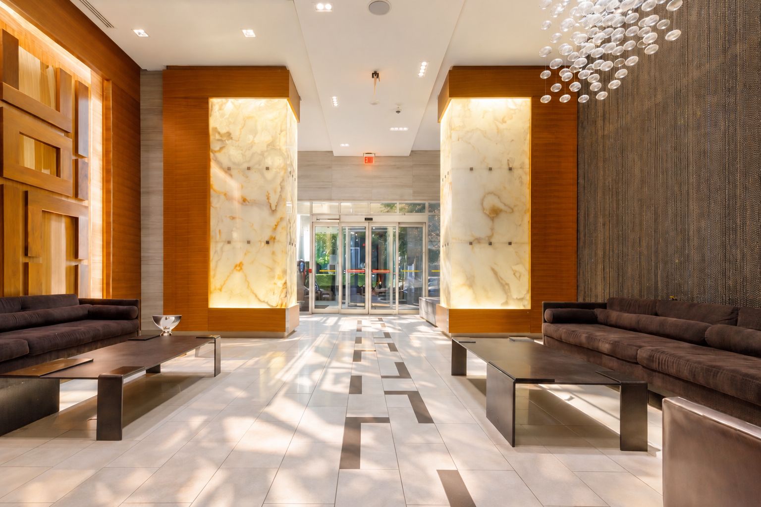 A modern lobby with marble walls, wooden accents, and a central seating area.