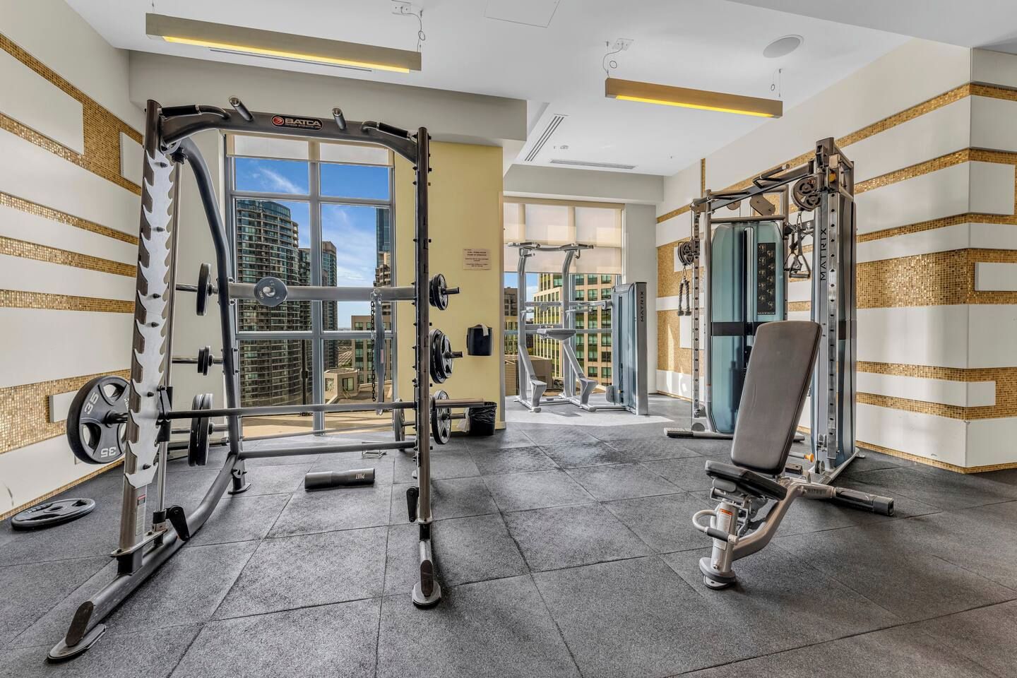 A modern gym with various exercise equipment, including a squat rack and a bench press.