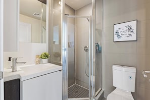 A modern bathroom with a glass-enclosed shower, a white sink, and a toilet. - The Colin Suites - Downtown Toronto (Toronto)