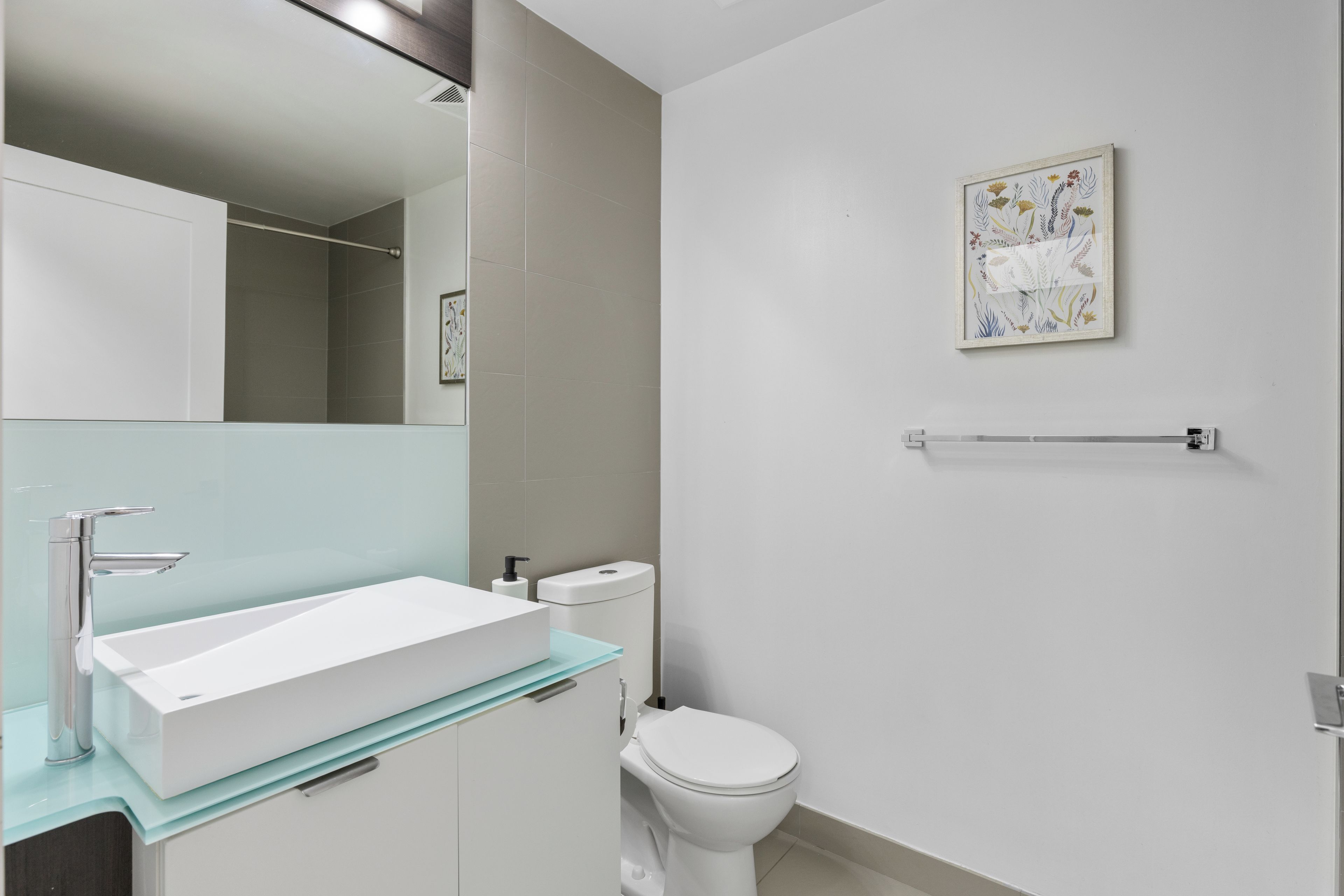 A modern bathroom with a white sink, a toilet, and a mirror.
