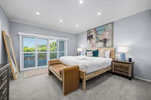 Ein Schlafzimmer mit einem großen Bett, einer hölzernen Bank, einem Nachttisch und einem Bild an der Wand.