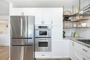 Eine moderne Küche mit Edelstahlgeräten, weißen Schränken und einem eingebauten Backofen.