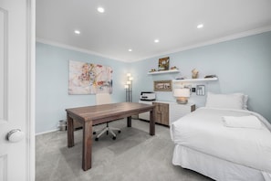 A bedroom with a bed, a desk, a chair, a lamp, and artwork on the wall. - Modern Home in a Quiet-Gated area w/ Pool & Spa. (Corona Del Mar)