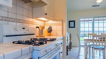 A modern kitchen with a gas stove, oven, and a view of the outdoors through a large window.