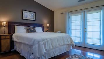 A hotel room with a large bed, two bedside lamps, a framed picture on the wall, and a view through the door.