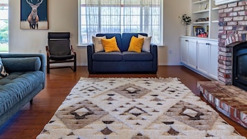 A living room with a sofa, armchair, and a patterned rug.