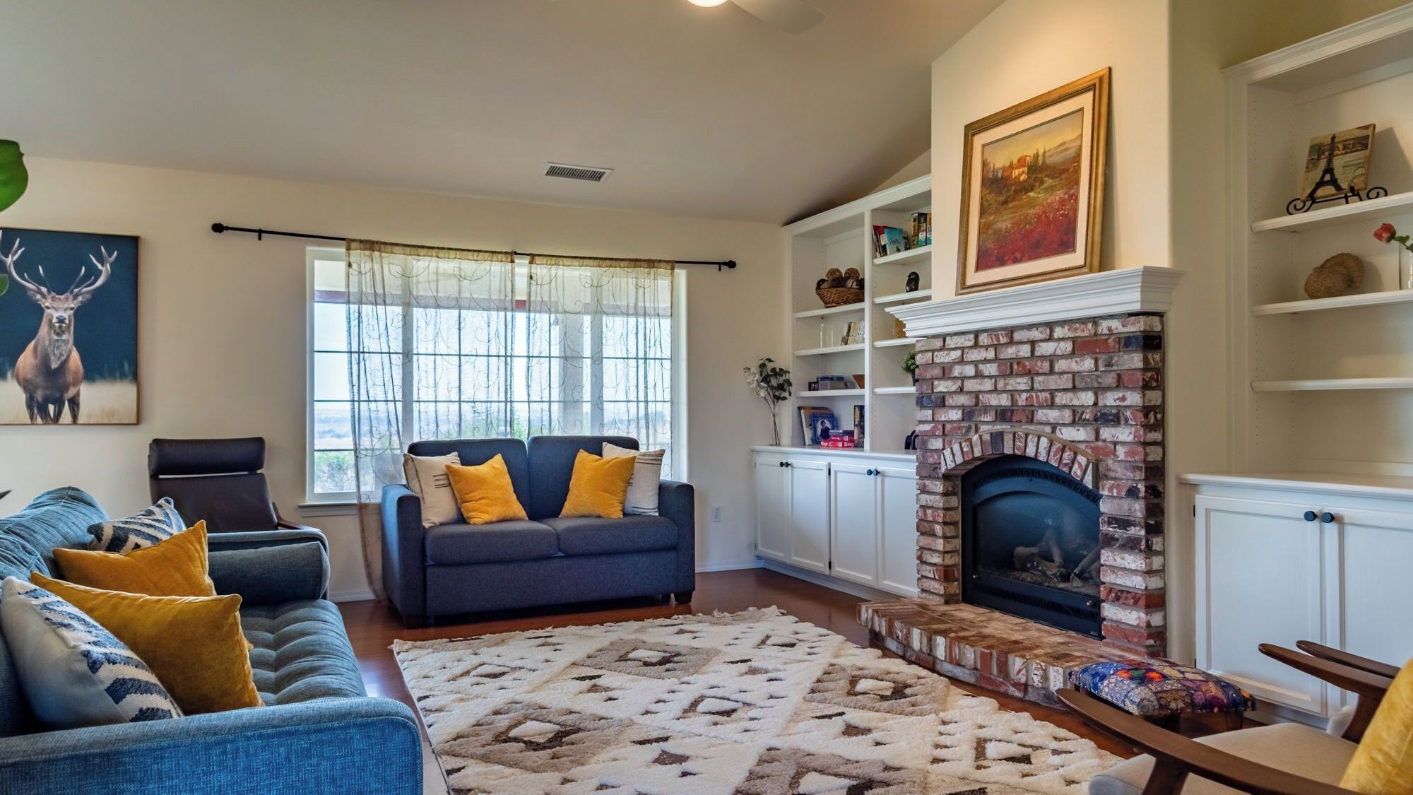 A living room with a fireplace, a sofa set, a rug, and a bookshelf.