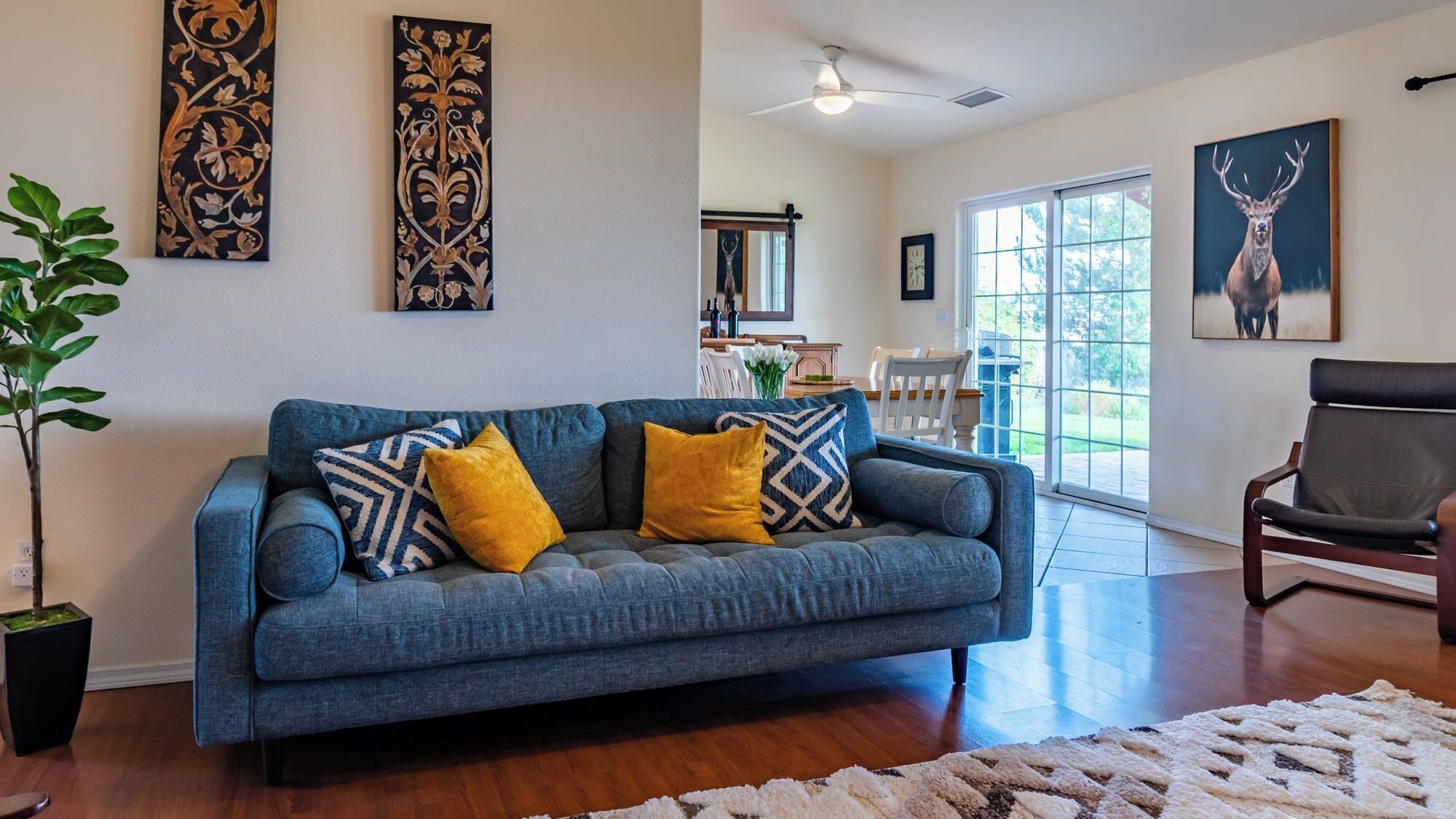 A living room with a blue sofa, a wooden floor, and artwork on the walls.