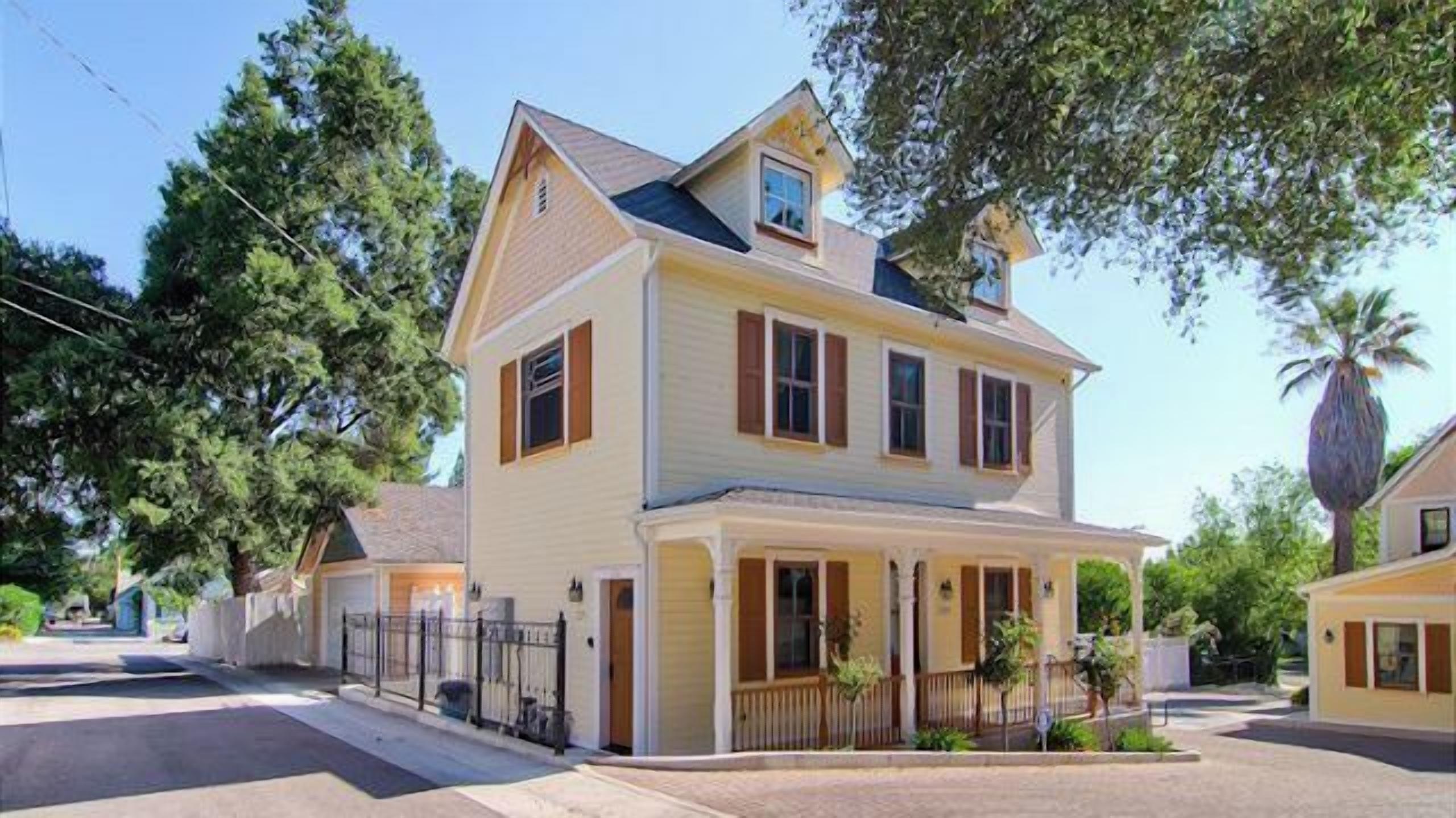 A two-story house with a front porch, a chimney, and a small attached garage.
