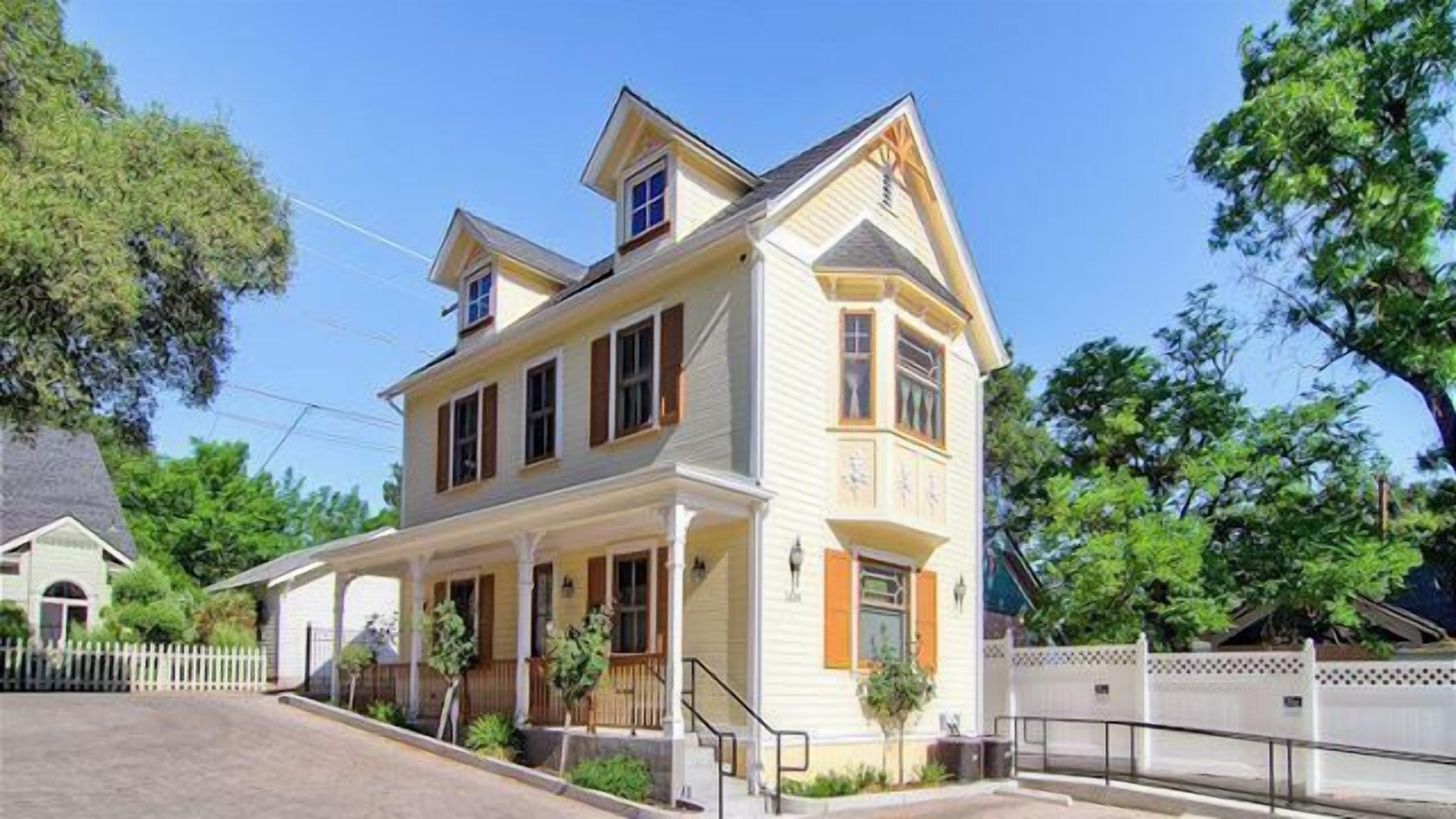 A two-story house with a porch, a front yard, and a white picket fence.