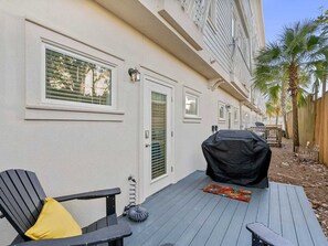 A covered outdoor seating area with a grill, a chair with a yellow cushion, and a wooden deck. - Amazing Rooftop Views | 2 Min Walk to Beach (Santa Rosa Beach)