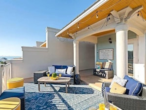 Ein Terrassenbereich im Freien mit Sitzgelegenheiten, einem Tisch und einem Hinweisschild.