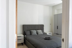 A bedroom with a bed, nightstands, a wardrobe, and a door. - Morden stay minutes from Manchester City centre (Manchester)