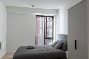 A bedroom with a bed, a wardrobe, and a window with blinds. - Morden stay minutes from Manchester City centre (Manchester)