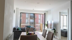 A modern dining area with a table, chairs, and a view of a brick building through large windows. - Morden stay minutes from Manchester City centre (Manchester)