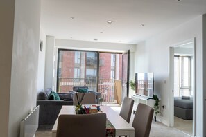A modern dining area with a table, chairs, and a view of a brick building through large windows. - Morden stay minutes from Manchester City centre (Manchester)