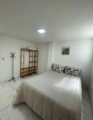A bedroom with a bed, a coat rack, a wardrobe, and a painting on the wall. - House 4 in the Anglo-Brazilian Village (São Paulo)