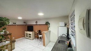 A compact kitchen with a sink, a small bar counter, a television, and a cabinet. - House 4 in the Anglo-Brazilian Village (São Paulo)