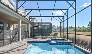 A swimming pool with a glass enclosure, outdoor seating, and a view of the surrounding landscape.
