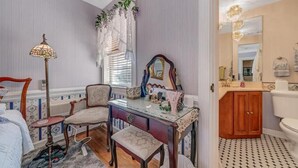 Un dormitorio con cama, escritorio, silla y ventana con cortinas.