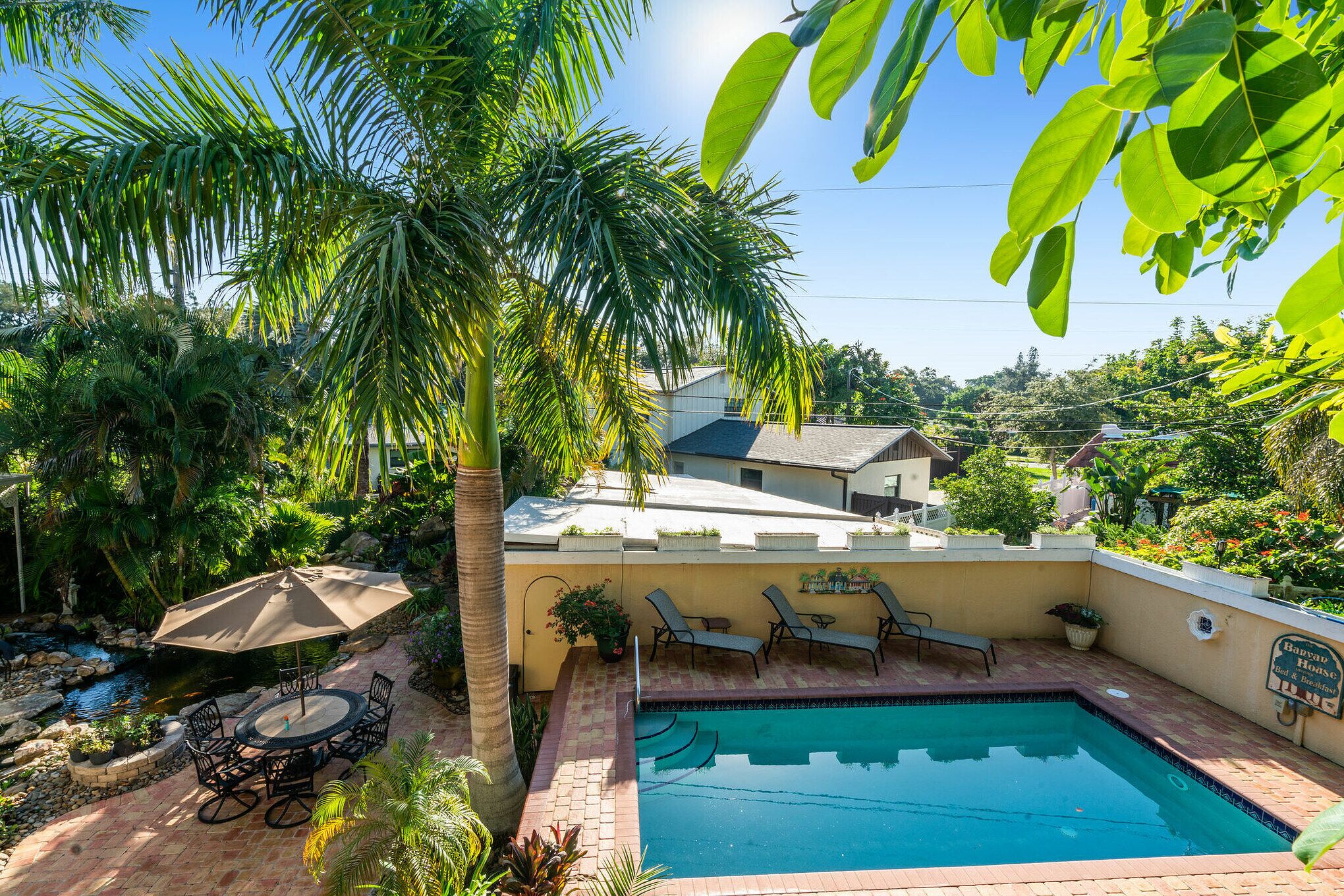 Ein Garten mit Swimmingpool, Liegestühlen, einem Tisch mit Stühlen und einer kleinen Grünanlage.