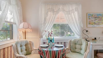 Una habitación con mesa, sillas y ventana con cortinas.