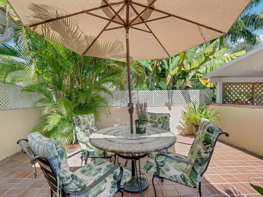 A patio with a round table, four chairs, and a large umbrella.