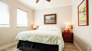 A bedroom with a bed, two bedside tables with lamps, a window, and a painting on the wall. - Charm on Chestnut by Avantstay Single-level + Fenced Yard + Gas BBQ Walk to Downtown Paso Robles (Paso Robles)
