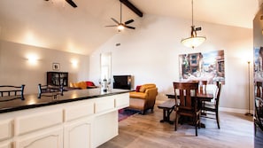 Un vaste espace de vie comprenant un îlot de cuisine, une table à manger et un coin salon confortable.