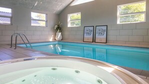 Una piscina con hidromasaje, paredes enlosadas y cuadros enmarcados.
