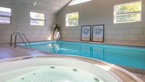 Ein Schwimmbecken mit Whirlpool, befliessten Wänden und gerahmten Bildern an der Wand.