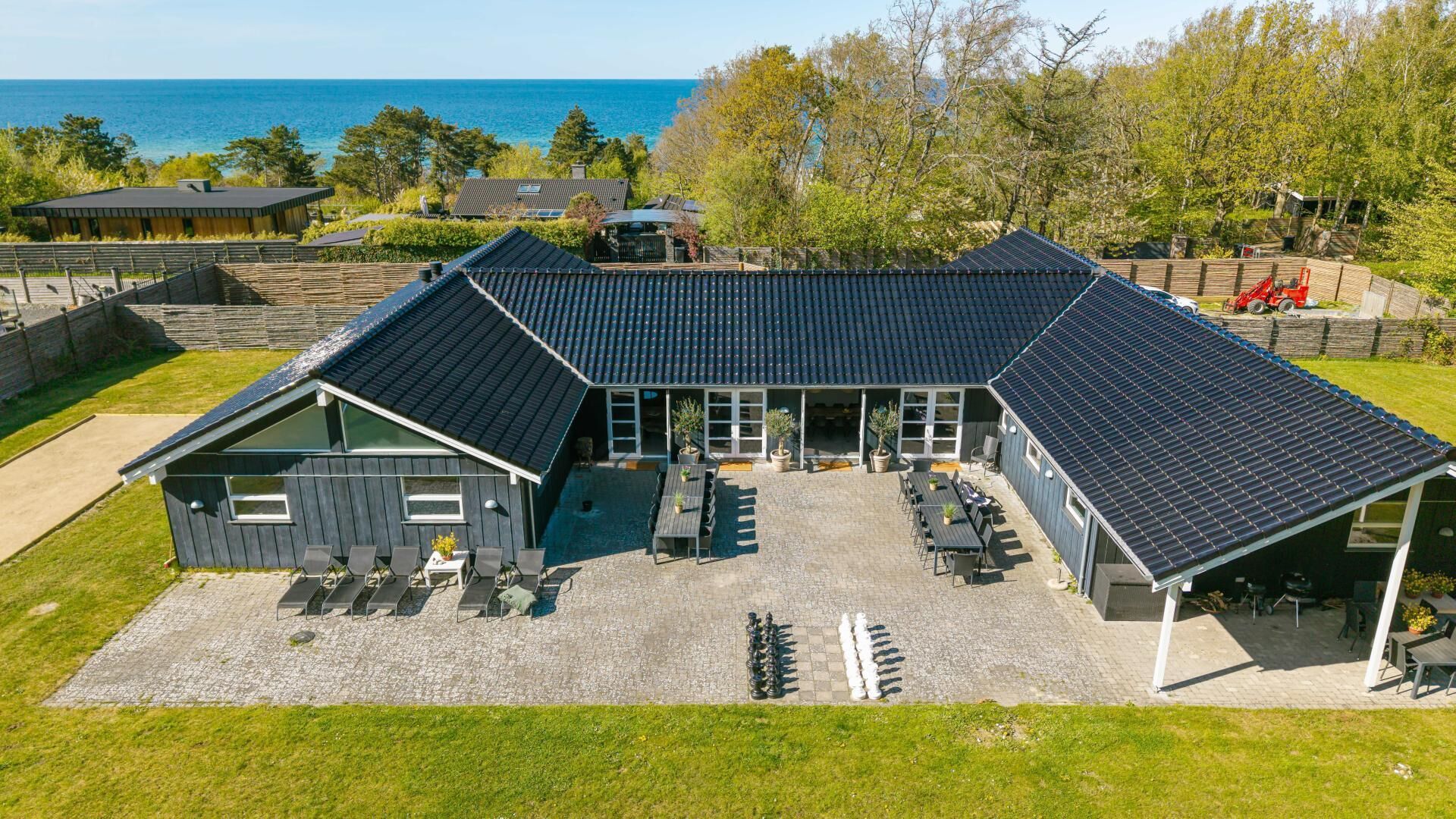 Un bâtiment doté d’un toit en pente, d’un espace extérieur aménagé pour s’asseoir et offrant une vue sur la mer.