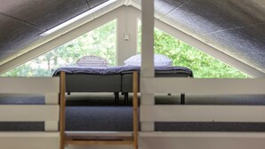 Una habitación tipo dormitorio con literas, una ventana y una escalera.