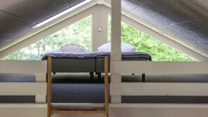 Ein Schlafraum im Mehrbettzimmerstil mit Etagenbett, Fenster und einer Leiter.