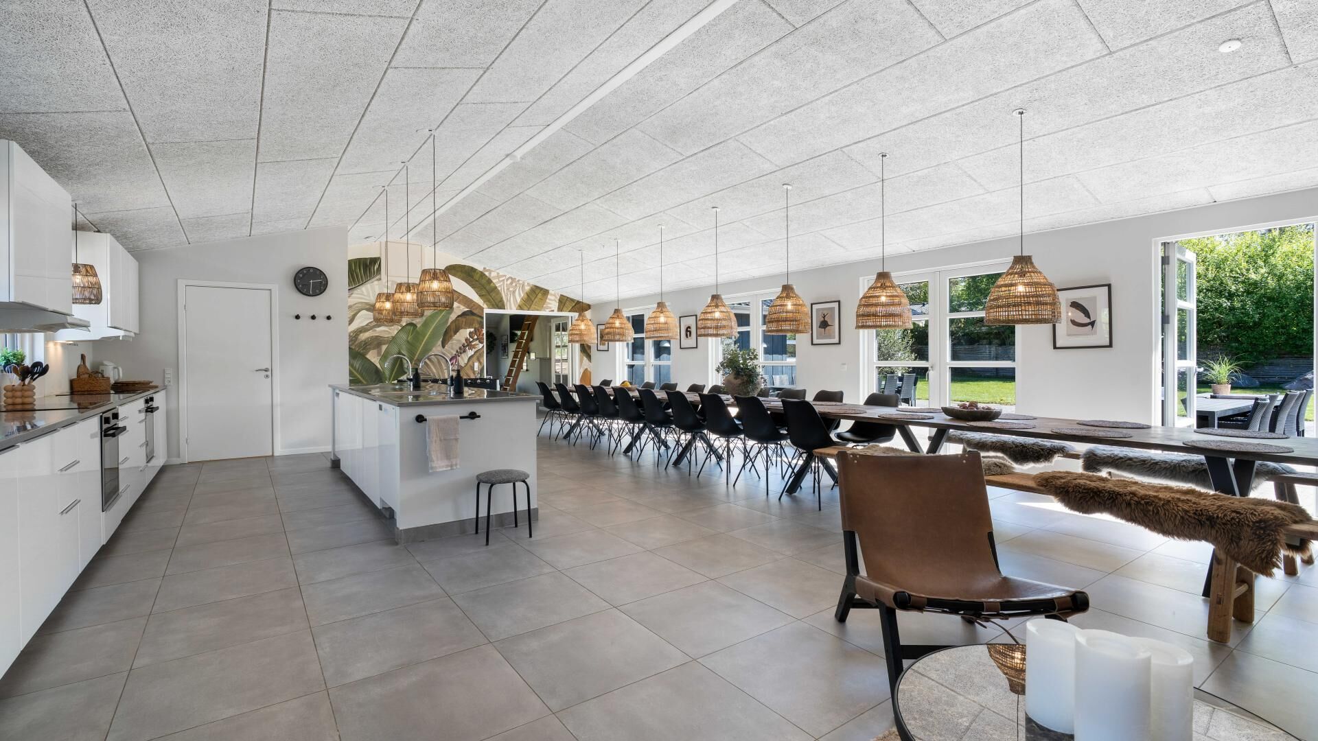Une cuisine moderne dotée d’un îlot central, d’un coin repas avec des chaises et d’un éclairage suspendu.