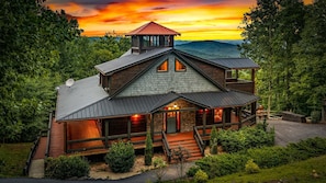 A multi-level wooden cabin with a stone facade, large windows, and a deck. - Raccoon Ridge - Mountain View | Pet Friendly | Hot Tub | Game Room | Firepit (Blue Ridge)