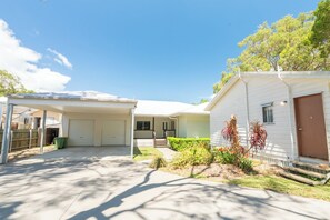 A residential property with a covered garage, a front porch, and a small garden area. - Sand Bar - Absolute Waterfront Escape, Amity Point (Amity Point)
