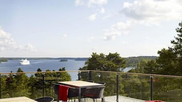 An outdoor deck with a table and chairs, overlooking a body of water and forested area.