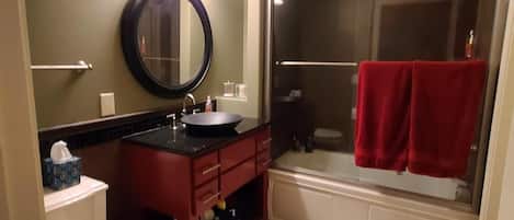 Et badeværelse med toilet, håndvask, spejl og bruseområde.