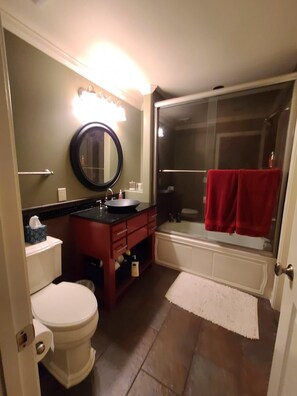 Ein Badezimmer mit Toilette, Waschbecken, Spiegel und Duschbereich.