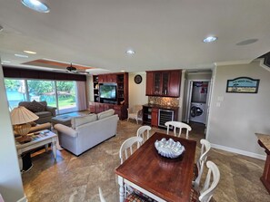 Un amplio salón con sofá, televisión y mesa de comedor.