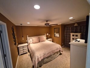 Ein Schlafzimmer mit einem Bett, Nachttischen, einem Deckenventilator und einer Kommode.