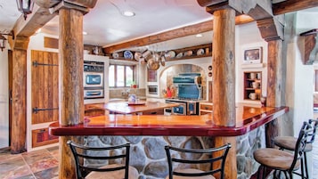 Una cocina con una isla central, paredes de piedra y vigas de madera.