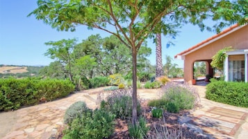 Un jardín ajardinado con un sendero de piedra que conduce a un edificio de techo rojo.