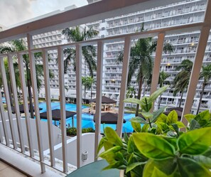 A hotel balcony with a view of a swimming pool and palm trees. - The Executive Suites - Shell Residences Manila 1BR Condo near MOA NAIA Ikea (Pasay City)