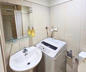 A bathroom with a white sink, a mirror, and a handheld shower unit. - The Executive Suites - Shell Residences Manila 1BR Condo near MOA NAIA Ikea (Pasay City)