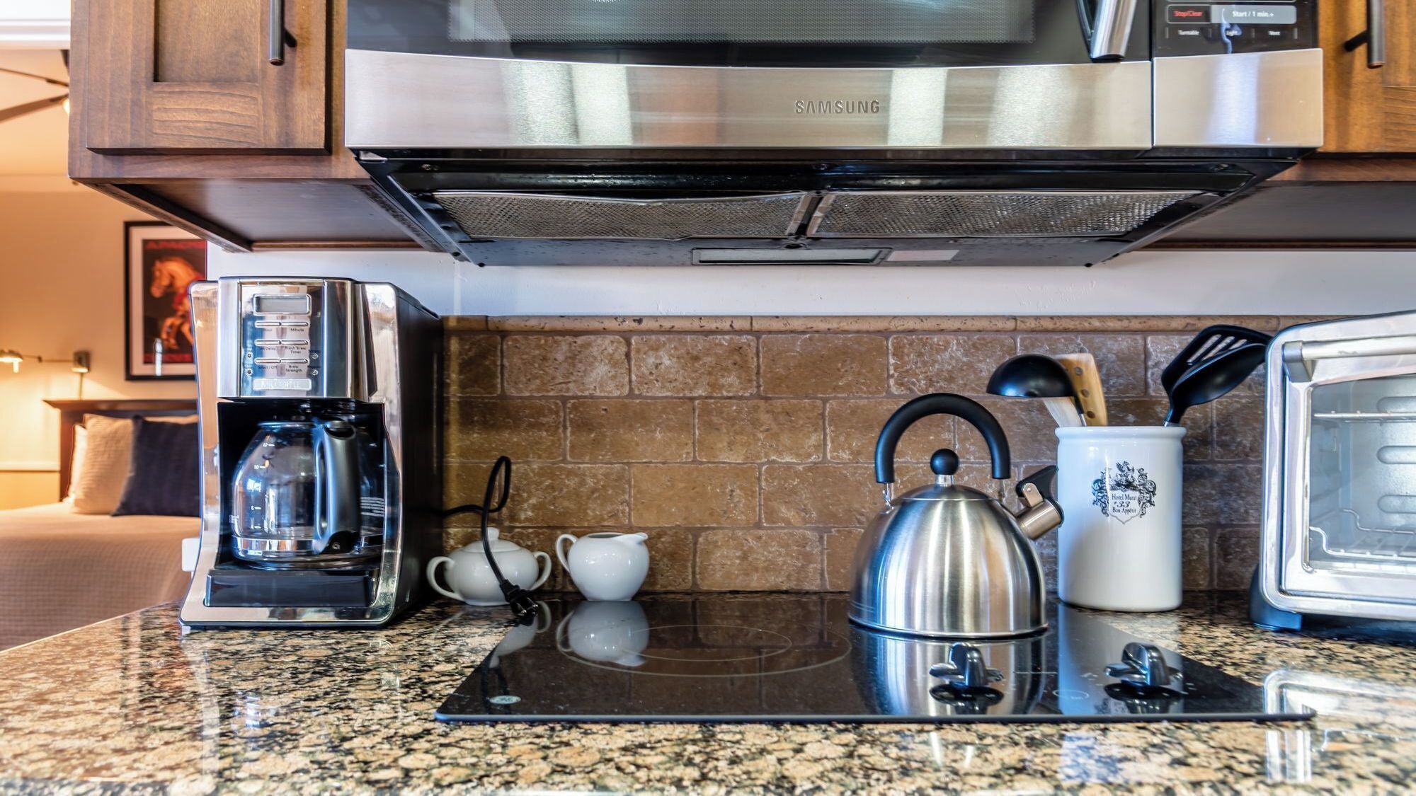 A kitchen with a microwave, coffee maker, kettle, and toaster.