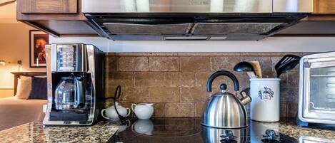 A kitchen with a microwave, coffee maker, kettle, and toaster.
